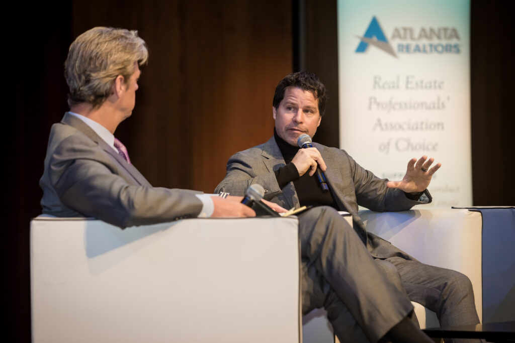 An image of two men on stage during a fireside chat at a corporate event photographed by Atlanta Corporate Events Photographer Karen Images