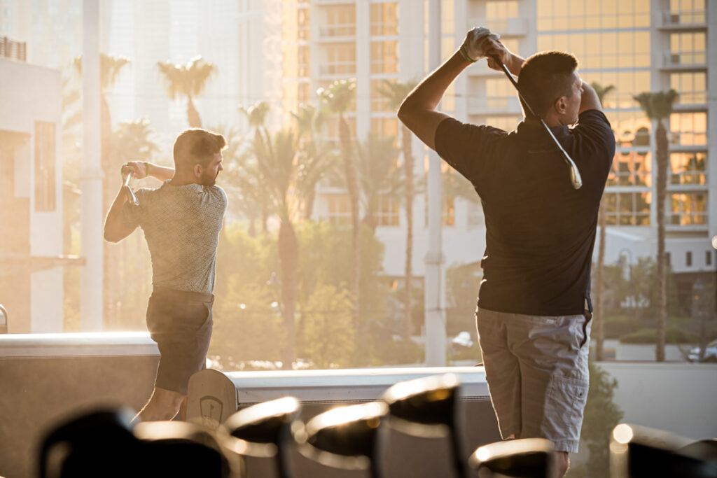 An image of men playing golf at Top Golf during a corporate event sponsored by Porsche photographed by Atlanta Commercial Photographer Karen Images