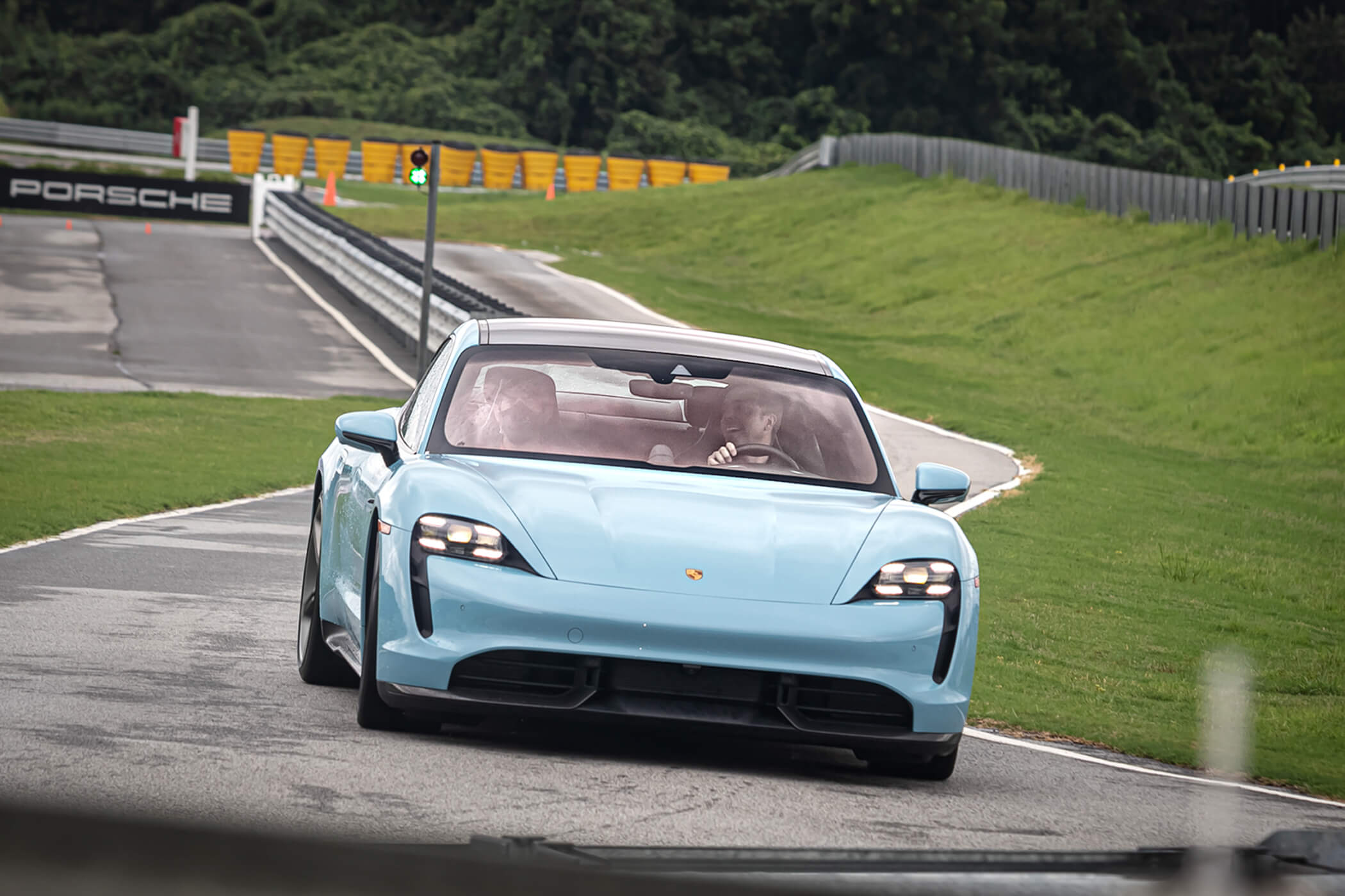 Light blue Porsche Taycan driving on the track at the Porsche Experience Center Atlanta