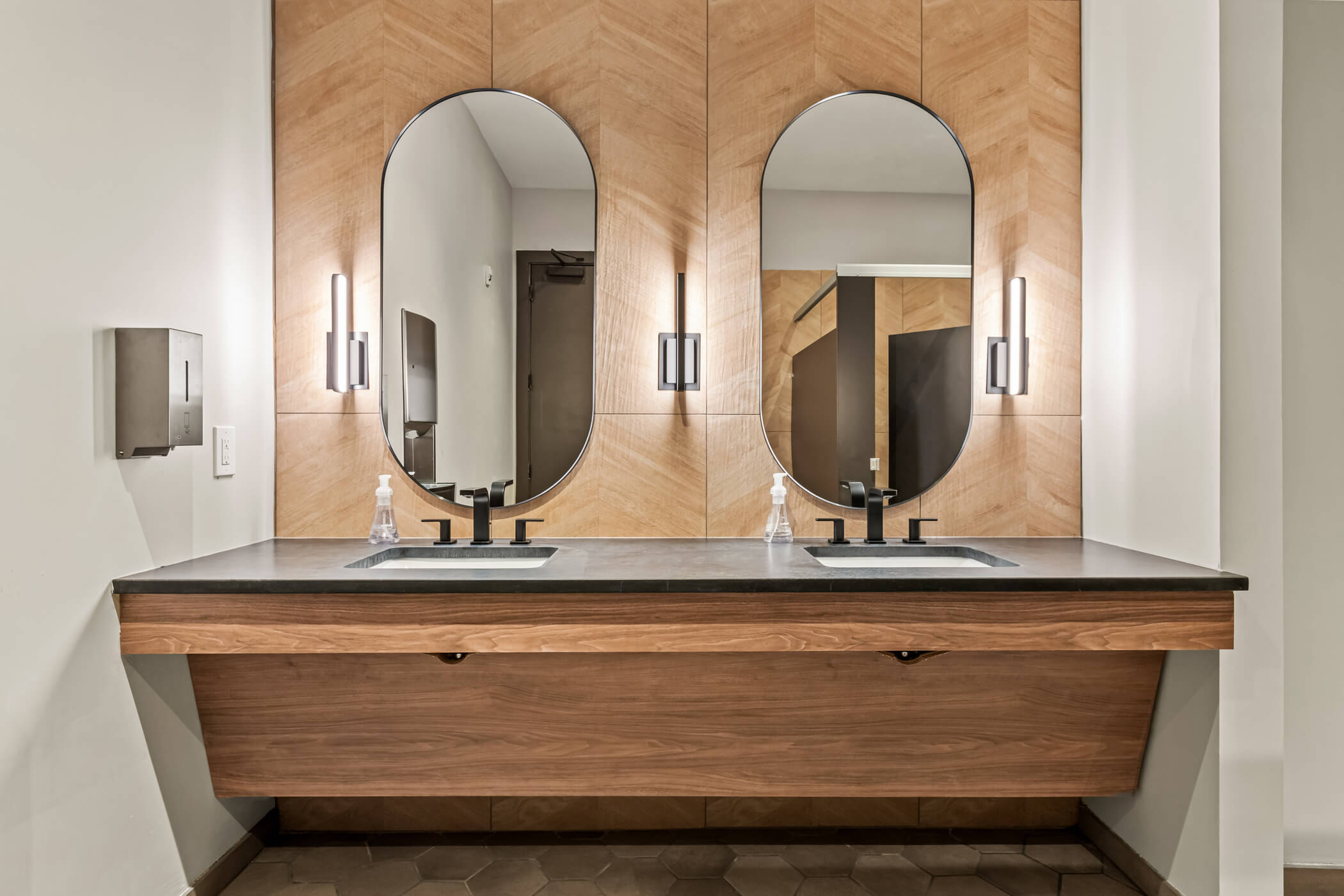 Multifamily amenity interior with double vanity, wood architectural finishes and contemporary mirrors