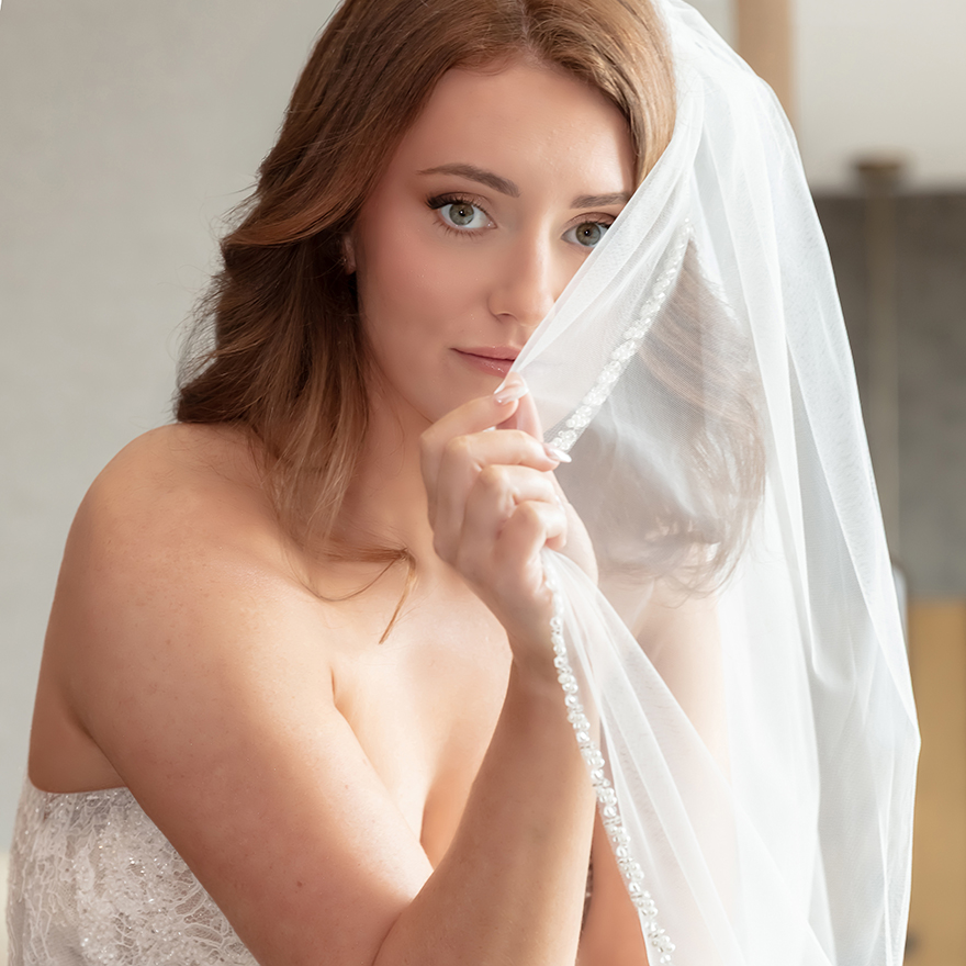 Bride holding vail looking at camera