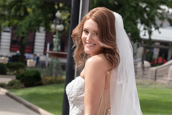 Bride smiling toward the camera while being filmed outdoors on her wedding day