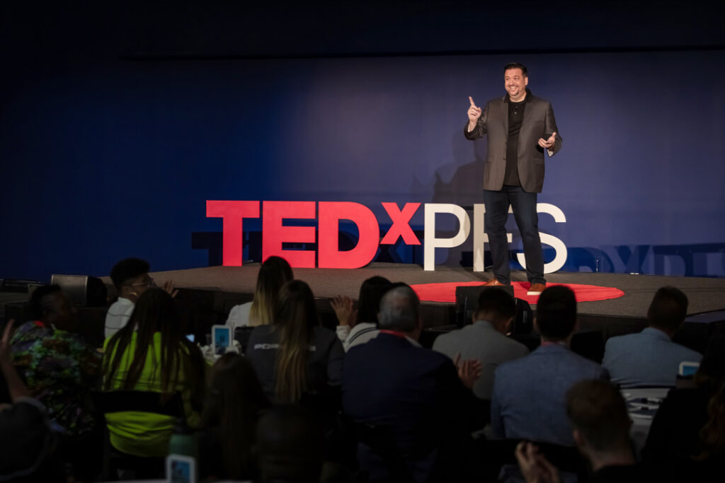 Speaker presenting on stage during a TEDx event