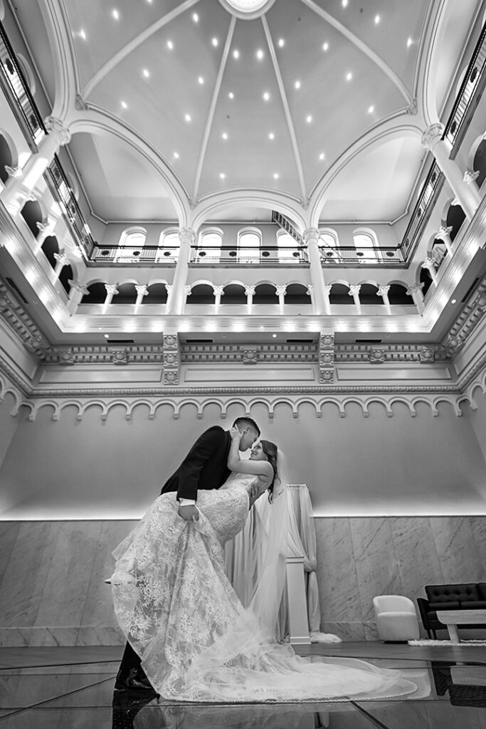 Bride and groom dancing beneath an ornate architectural ceiling during their luxury wedding celebration