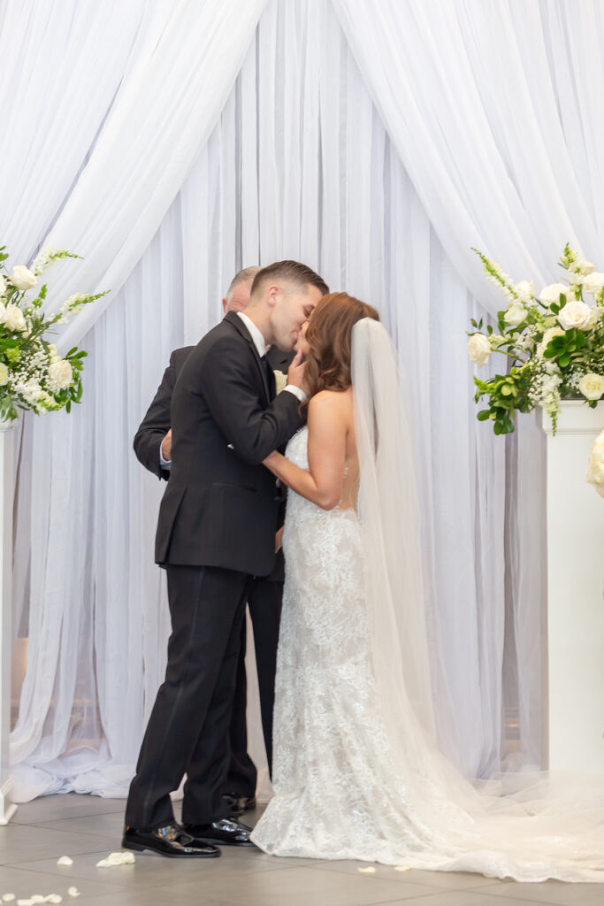 Bride and groom sharing their first kiss during their wedding ceremony at Limestone Hall in Lexington, Kentucky